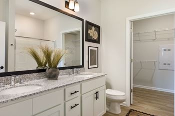 A bathroom with a white toilet and a large mirror above the sink.